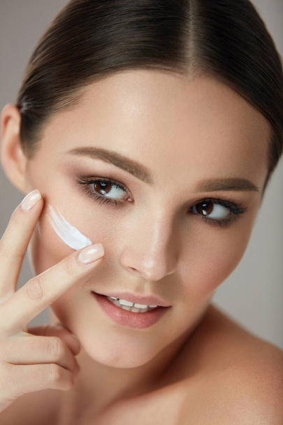 Facial Care. Closup Beautiful Woman Putting Skin Cream On Face - Fotó, kép