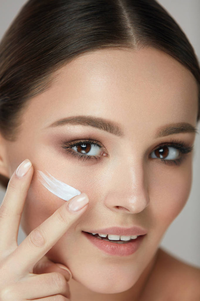 Facial Care. Closup Beautiful Woman Putting Skin Cream On Face - Foto, afbeelding