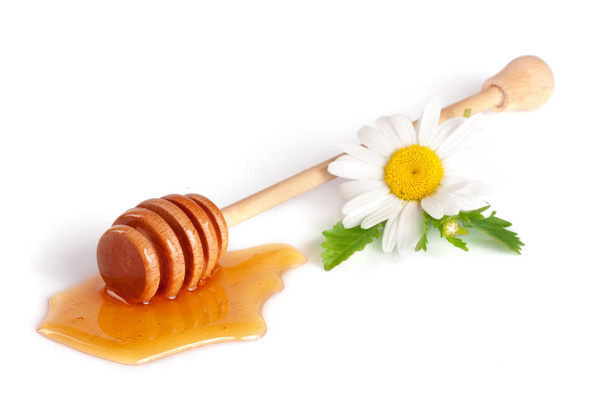Μέλι ραβδί με ρέει μέλι και λουλούδια χαμομηλιού που απομονώνονται σε λευκό φόντο - Φωτογραφία, εικόνα
