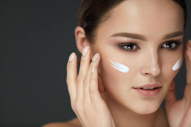 Beautiful Woman With Fresh Makeup Applying Cream On Beauty Face - Foto, Imagem