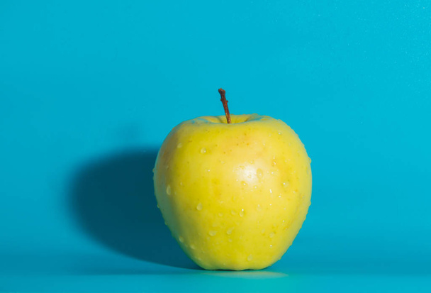 on a blue background yellow Apple, close up. - Foto, Imagen
