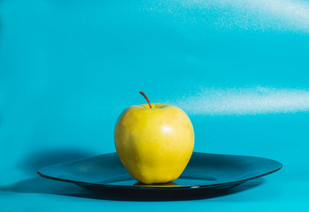yellow Apple in the plate on a blue background. - Foto, Imagen