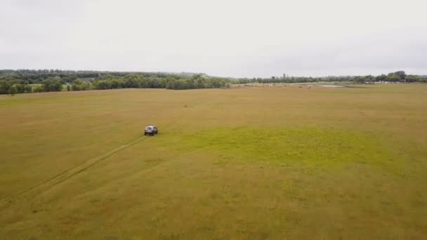 Antenne. über dem Geländewagen fliegen, der schnell im Gelände durch ländliche Gegenden fährt - Filmmaterial, Video