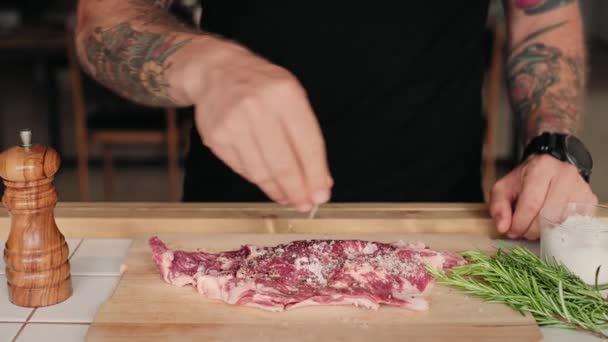 Man marinates and seasons fresh steak with spices - Кадры, видео