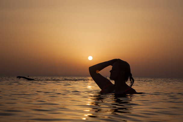 silueta de una chica en el océano al atardecer, mujer del océano al amanecer l
 - Foto, imagen
