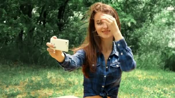 attractive woman sitting on the street and makes a photo on your phone - Video, Çekim