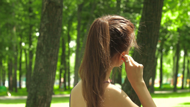 junges Mädchen setzt Kopfhörer in die Ohren und rennt - Filmmaterial, Video
