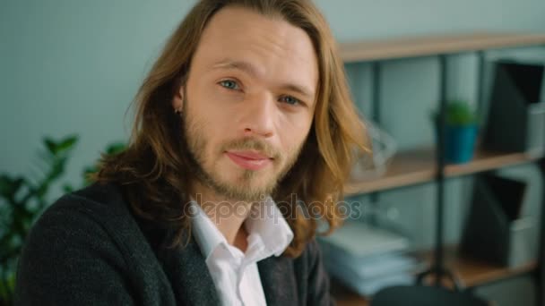 Close up portrait of long hair businessman looking kindly at the camera. Smiling young man portrait at office. - Footage, Video