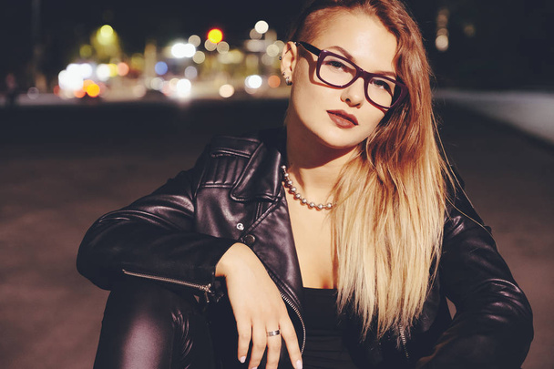 Sexy woman with long hair in leather clothes on night city lights background - Photo, Image