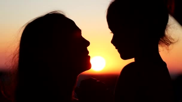 Silhouettes of mother and her daughter heads. Mom kissing her child. - Filmagem, Vídeo