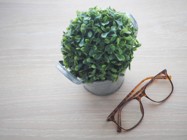 モダンな眼鏡と花の小さなツリー木製オフィス テーブル - 写真・画像