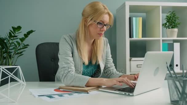 Attractive blonde businesswoman working with laptop computer at the office - Imágenes, Vídeo
