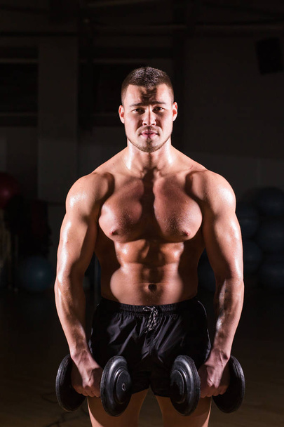 Muscular bodybuilder guy doing exercises with dumbbells. - Zdjęcie, obraz