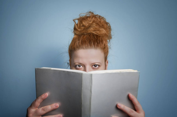 Krásná dívka drží otevřenou knihu. Selektivní ostření na oči. - Fotografie, Obrázek
