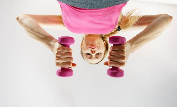 Teenage woman working out at home with dumbbell - Foto, imagen