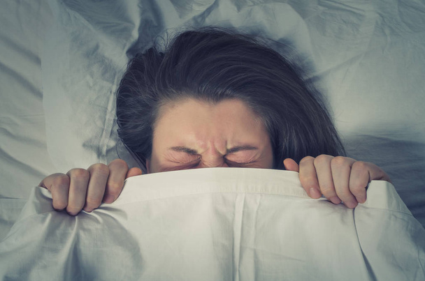 Woman  hiding behind sheet in bed. - Foto, Bild