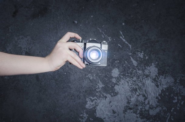 Męskiej ręki trzymającej aparat fotograficzny retro na tle szarej ścianie - Zdjęcie, obraz
