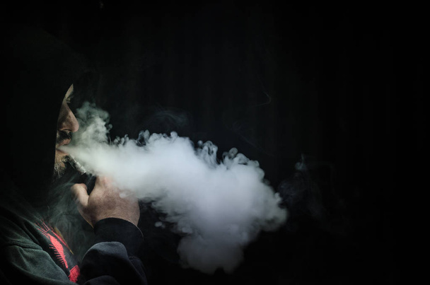 Vaping ember, aki egy mod. Egy felhő-ból gőz. Fekete háttér. Vaping elektronikus cigaretta füst egy csomó - Fotó, kép