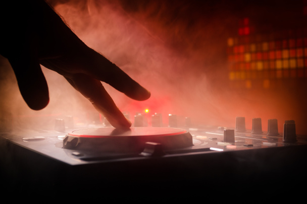 DJ Spinning, Mixing, e Scratching in a Night Club, Mãos de dj ajustam vários controles de pista no deck do dj, luzes estroboscópicas e nevoeiro, foco seletivo
 - Foto, Imagem