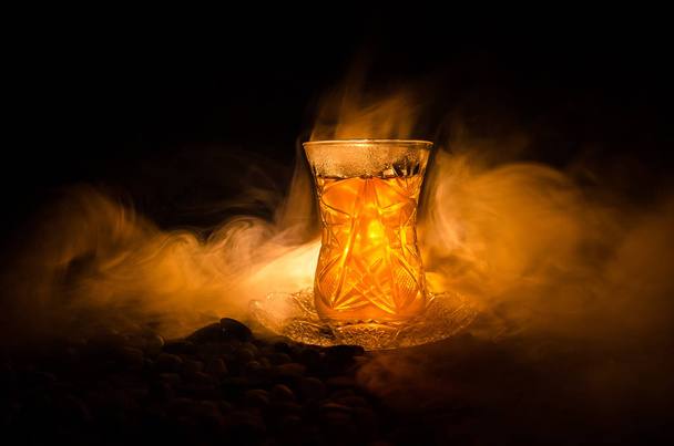 Turkish Azerbaijan tea in traditional glasse and pot on black background with lights and smoke. Armudu traditional cup - Fotoğraf, Görsel