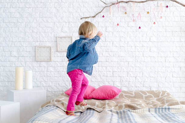 Happy child girl jumps on bed - Φωτογραφία, εικόνα