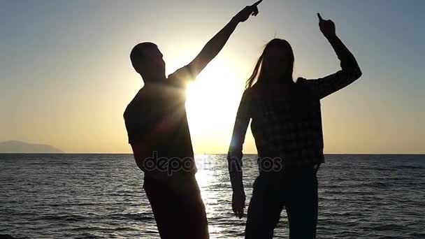 Fiatal férfi és a nő tánc a festői tengerparton naplementekor, lassítva - Felvétel, videó