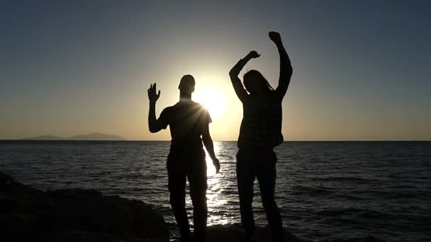 Boldog férfi és nő Frolick és táncolnak a tengerparton napnyugtakor a Slo-Mo - Felvétel, videó