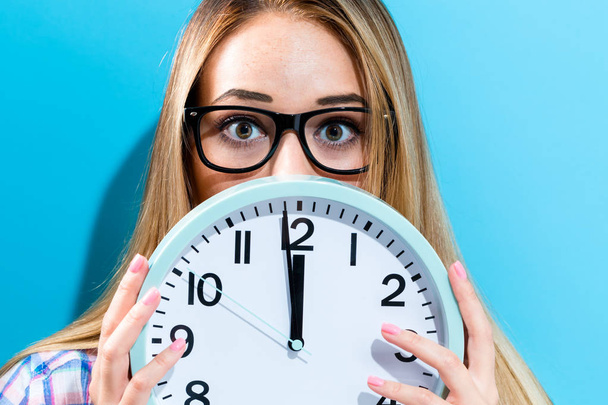 Woman holding clock showing nearly 12 - 写真・画像