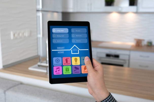 человек держит в руках планшетное приложение смарт-дом фоновой комнате кухня
 - Фото, изображение