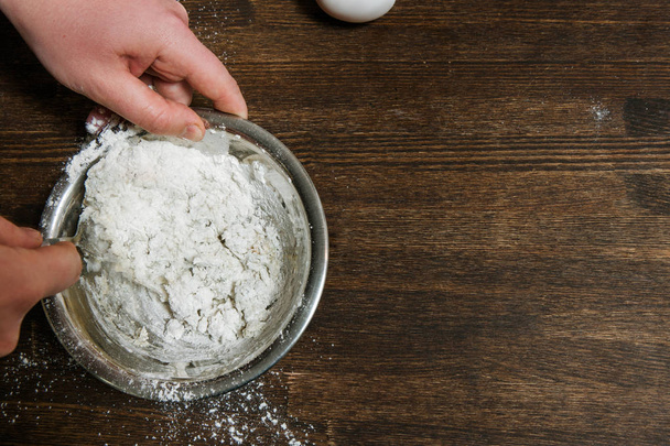 Chief mixes dough in bowl on table - Φωτογραφία, εικόνα