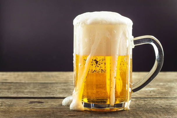 Pouring beer into a glass on a wooden table. Alcoholic beverages. Alcohol-free beer. Sale of beer to the bar. - Foto, Bild