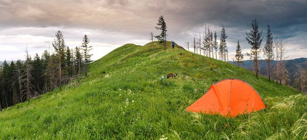 Tienda de senderismo naranja en la cima de la colina debajo de la hierba fresca, concepto de ocio al aire libre de verano
 - Foto, imagen