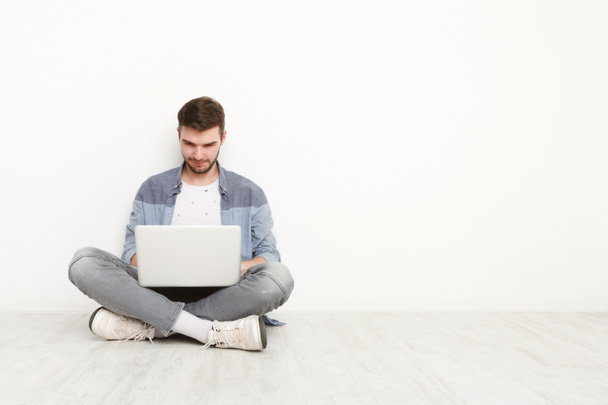 Młody mężczyzna pracujący na laptopie siedząc na podłodze - Zdjęcie, obraz