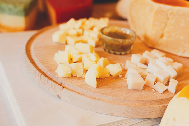 Сырное блюдо, пармезан на натуральной деревянной тарелке с соусом
 - Фото, изображение