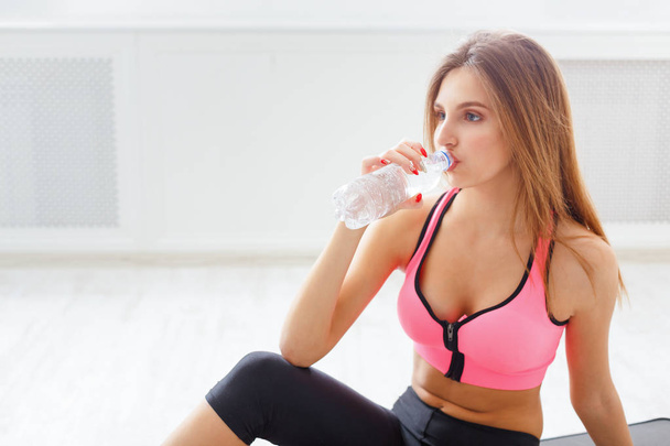Красива молода спортивна жінка п'є воду
 - Фото, зображення