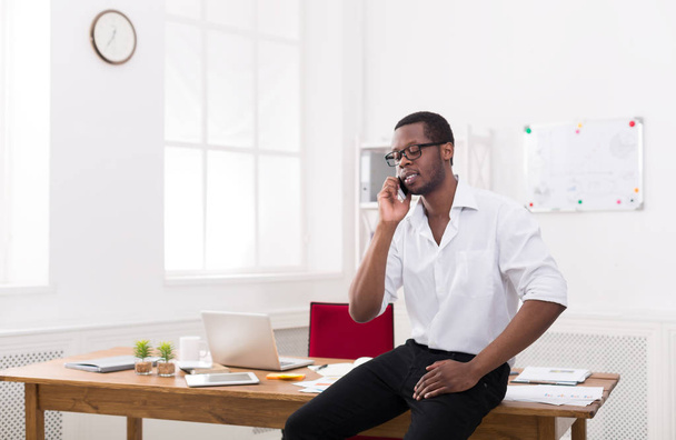 Joven hombre de negocios negro con móvil en la oficina blanca moderna
 - Foto, imagen