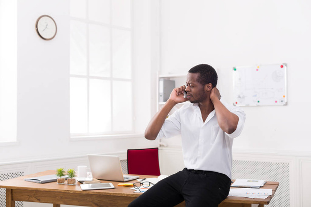 Upset black businessman with mobile in modern white office - Foto, afbeelding