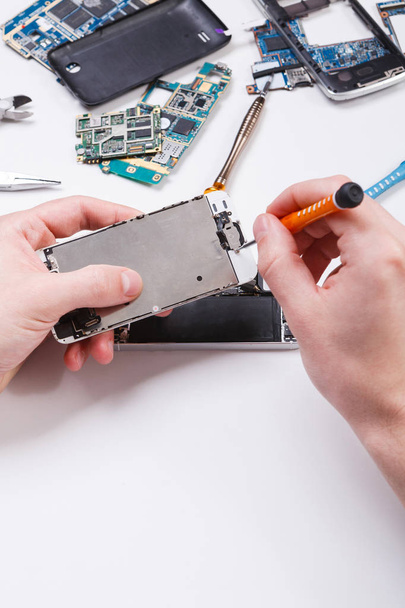Reparateur demontiert Telefon mit Schraubenzieher - Foto, Bild