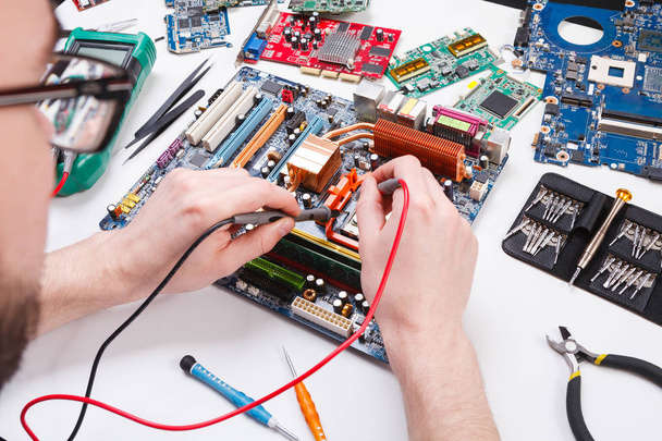 Engineer checking motherboard with multimeter - Photo, image