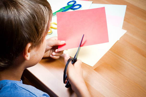 Dziecko, cięcia kolorowego papieru nożyczkami przy stole - Zdjęcie, obraz