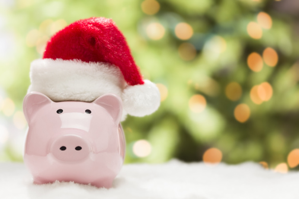 Pink Piggy Bank with Santa Hat on Snowflakes - Photo, Image