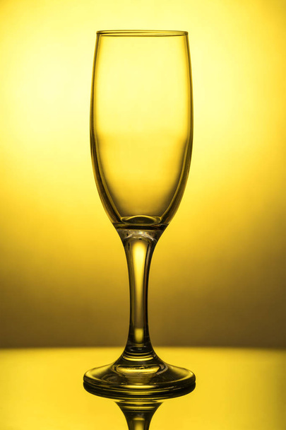 Empty wine glass on a yellow background - Foto, imagen