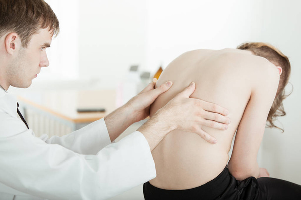 Médico examinando dolor de espalda músculos de adolescente chico
 - Foto, Imagen