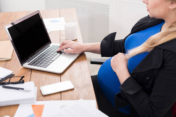 Вагітна жінка працює на ноутбуці з порожнім екраном
 - Фото, зображення
