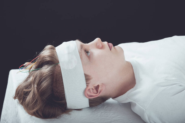 Chłopiec w pozycji leżącej z bandaże owinięte wokół głowy - Zdjęcie, obraz