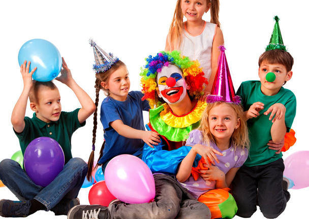 Клоун на день народження грає дітей. Дитина в капелюсі вечірки тримає повітряні кулі
 . - Фото, зображення