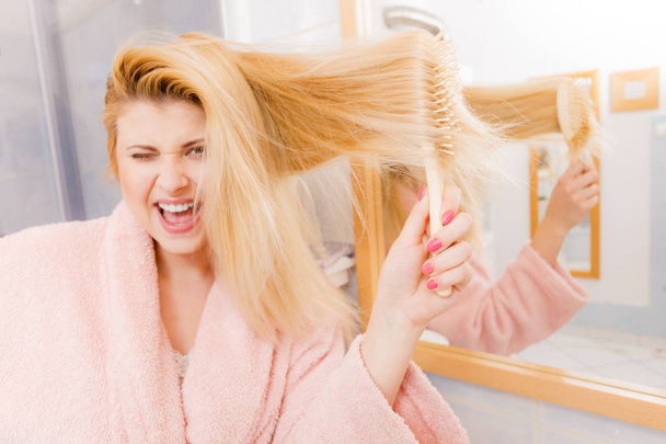 Woman wearing dressing gown brushing her hair - Photo, Image