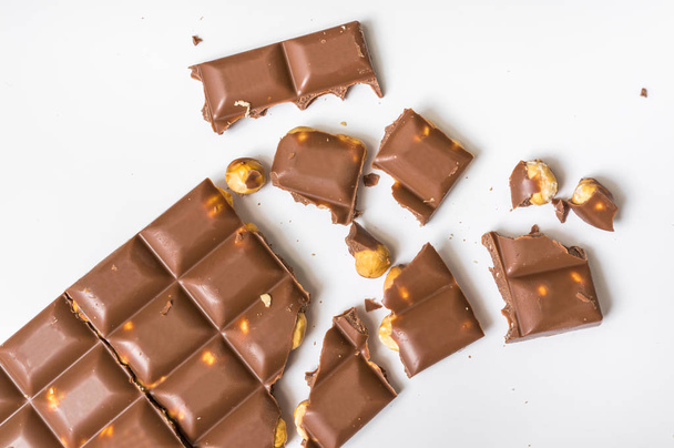 Broken chocolate bar with nuts isolated on white - Φωτογραφία, εικόνα