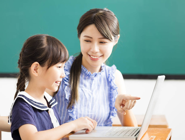 mladý učitel pomoci dítě s počítači lekce - Fotografie, Obrázek