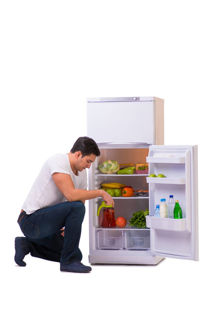 Ο άνθρωπος δίπλα στο ψυγείο γεμάτο τρόφιμα - Φωτογραφία, εικόνα